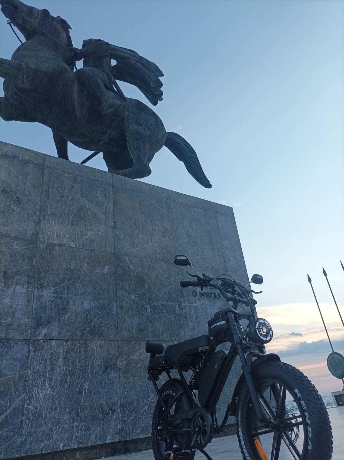 Το ηλεκτρικό fat bike Zeuron X80 Pro φωτογραφημένο κάτω από το άγαλμα του Μεγάλου Αλεξάνδρου στη Νέα Παραλία Θεσσαλονίκης κατά το ηλιοβασίλεμα