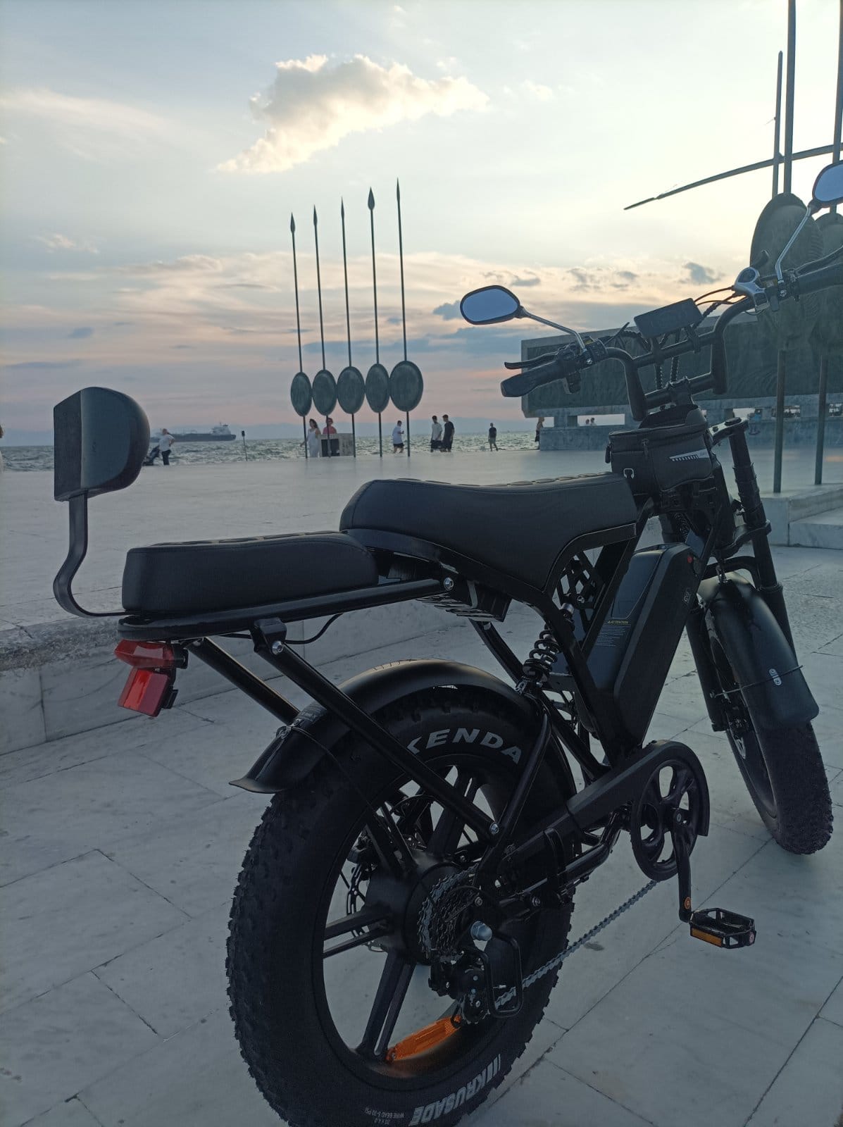 Ηλεκτρικό fat bike Zeuron X80 Pro μπροστά από το γλυπτό Ομπρέλες του Ζογγολόπουλου στη Νέα Παραλία Θεσσαλονίκης κατά το ηλιοβασίλεμα